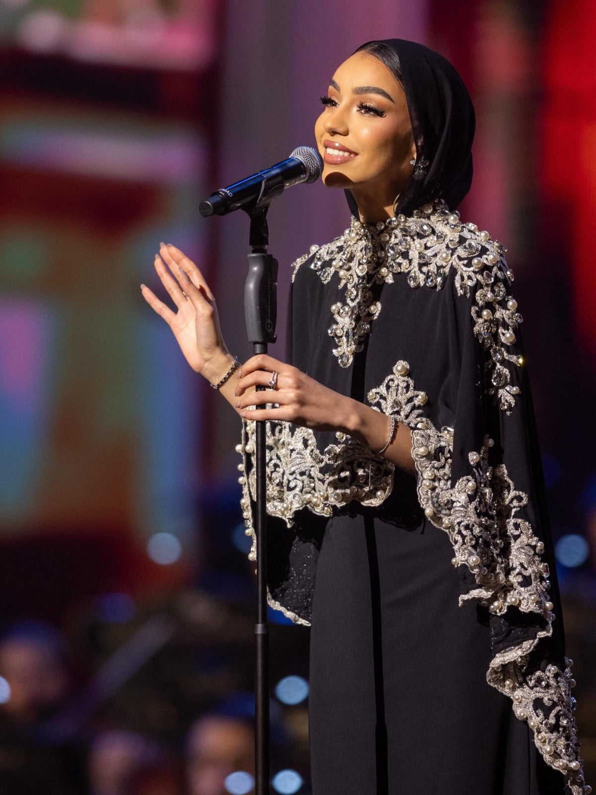 Dodona Moments: black cape gown with silver embroidery, on stage